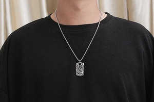 Close-up of a silver dragon pendant on a box chain worn by a male model