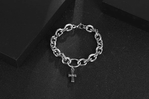 Detail of silver stainless steel chain bracelet with a vintage Gothic cross charm