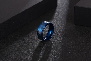 Vue macro d'une bague en acier bleu avec gravure de guitare et texture métal brossé