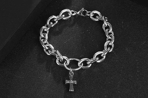 Detailed view of silver stainless steel chunky chain bracelet with cross charm on black surface