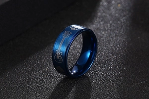 Gros plan d'une bague bleue en acier brossé avec des motifs de guitare et d'arbre gravés