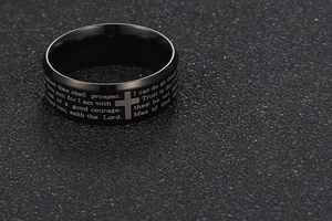 Macro view of black stainless steel ring featuring engraved Bible verses and cross symbol