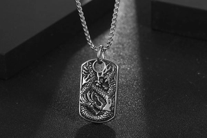 Macro detail of 3D dragon relief on silver titanium steel pendant with box chain