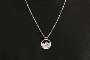 Vue détaillée du collier pendentif montagne en titane argenté sur fond noir texturé