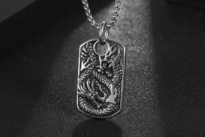 Detailed close-up of a vintage silver dragon relief on a rectangular titanium steel pendant