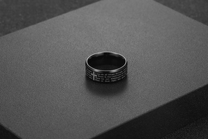 Macro detail of black stainless steel ring featuring laser-engraved Bible verse and cross