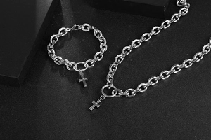 Macro detail of silver stainless steel necklace and bracelet with gothic cross pendant
