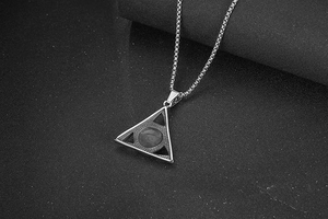 Macro detail of silver triangular evil eye pendant necklace with black round inlay