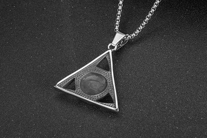 Macro detail of silver titanium steel Evil Eye pendant with triangle frame on black surface