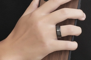 Detailed close-up of men's black stainless steel ring with cross and scripture engraving