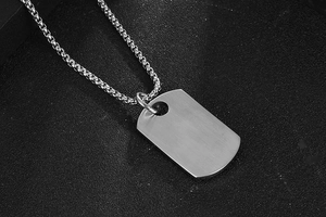 Macro shot of silver titanium steel dog tag pendant with brushed metal texture and box chain
