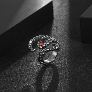 Gothic octopus stainless steel ring with red gemstone set on a black textured background