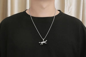 Detail of vintage silver honey badger pendant on square pearl chain worn by a man