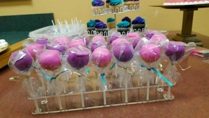 Clear acrylic cake pop stand with 21 holes holding colorful frosted desserts at a party