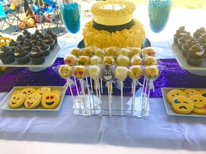 Detailed arrangement of Emoji cake pops and themed desserts on an acrylic party stand