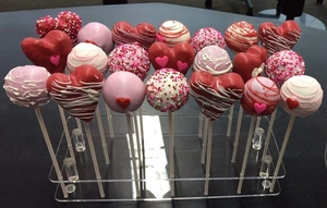 Detailed view of clear acrylic tiered stand holding heart shaped cake pops for weddings