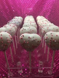 Detail of heart-shaped cake pops with colorful sprinkles on a clear acrylic stand