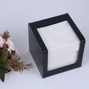Macro detail of black square acrylic tissue box with stack of white napkins inside