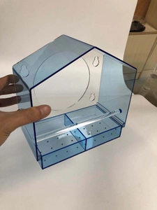 Detail view of transparent acrylic bird feeder with dual feeding slots and bird perch