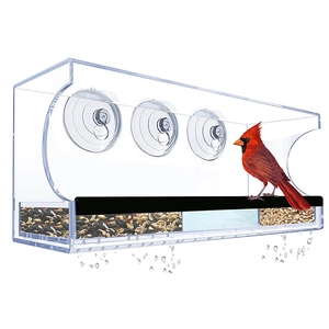 Macro detail of acrylic window bird feeder featuring drainage holes and separate food trays