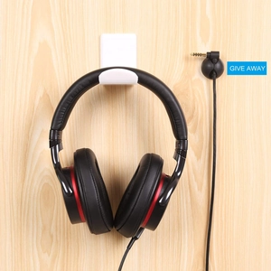 Under desk white acrylic headphone hook with black cable organizer on wood wall