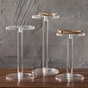 Three-tier clear acrylic jewelry display stands on a wooden surface for multi-level showcase