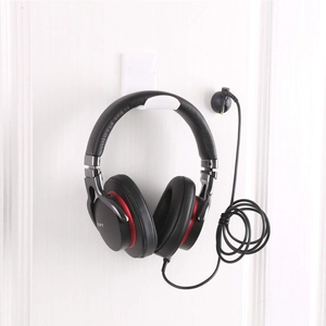 White under-desk acrylic headphone holder and cable clips mounted on wall for headset storage