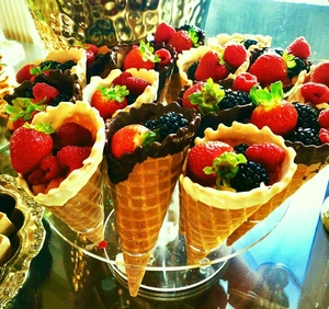 Close-up of fresh berry waffle cones with chocolate coating on a clear acrylic stand