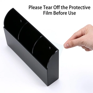 Black acrylic wall-mounted 3-slot remote control holder showing protective film removal