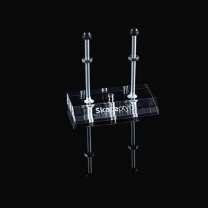 Wall-mounted clear acrylic skateboard rack with metal support bolts on black background