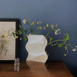 Vaso a specchio ondulato moderno e futuristico con superficie riflettente e margherite
