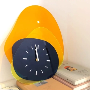 Artistic modern acrylic clock with orange and yellow geometric plates on white wall