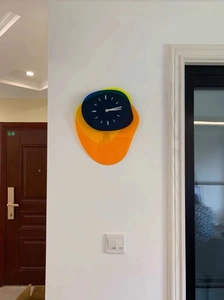 Close-up of abstract acrylic wall clock featuring layered blue, yellow and orange shapes