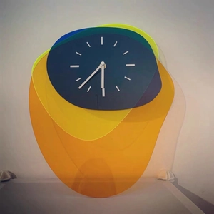 Detail of multi-layered acrylic wall clock with abstract blue, yellow, and green elements