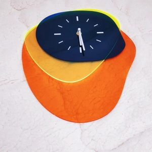 Detail of multi-layer acrylic wall clock featuring vibrant orange and yellow color blocks