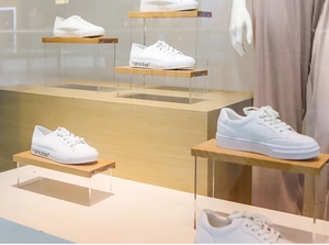 White low-top sneakers with STYLE66 lettering on professional acrylic display stand
