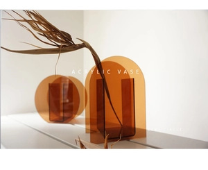 Detailed view of amber acrylic vases in minimalist arch and circle shapes with dried flowers