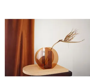 Close-up of amber acrylic geometric flower vase with minimalist dried palm leaf decoration
