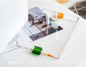 Macro detail of a minimalist transparent acrylic tray with vibrant orange and green handles