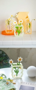 Detail of checkered acrylic flower vases in green and orange with wavy edges and daisy