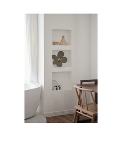 Detailed view of green flower-shaped wall clock with pink center in modern minimalist interior
