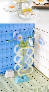 Detailed view of checkered acrylic vase with daisy smiley and poppies on pegboard background