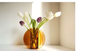 Detailed view of amber acrylic geometric vase with sunlight shadows and tulips