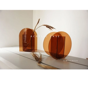 Close-up of amber acrylic arch vase with geometric design on a grey wooden surface