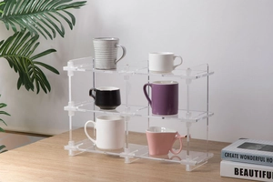 Three-tier clear acrylic storage rack for cups and collectibles on a wooden desk