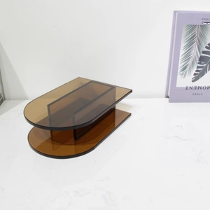 Detail of amber acrylic arched U-shaped tiered display shelf on marble surface