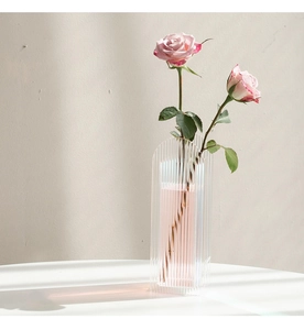 Detail view of modern arched fluted acrylic vase with vertical texture and fresh roses