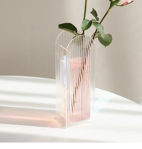 Close-up of ribbed acrylic vase with iridescent light effects on a white surface