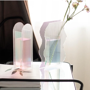 Detail of wavy acrylic vase with vertical ribs showing pink and blue iridescent light effects