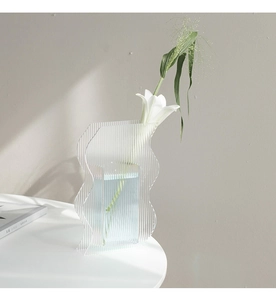Detailed view of modern ribbed acrylic vase with white lily and natural light shadows